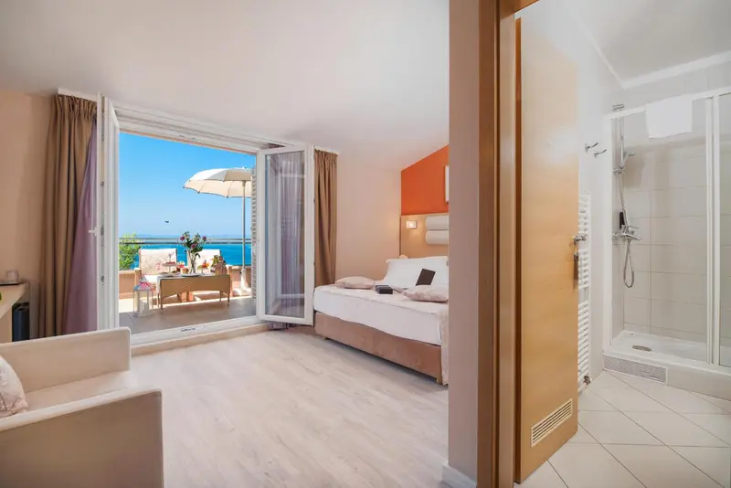 Une chambre lumineuse s'ouvre sur une terrasse avec vue sur la mer.