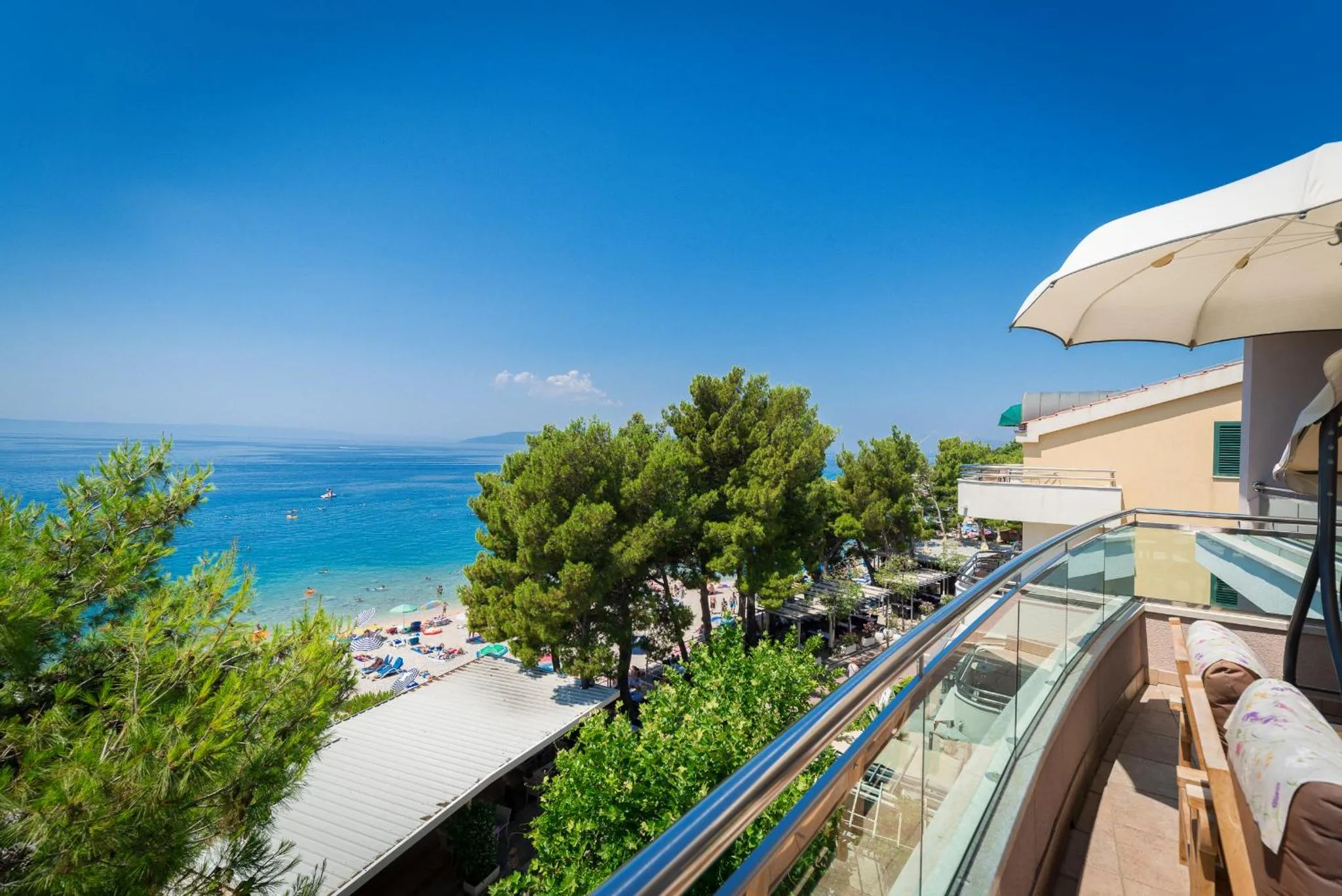 Vue d'une terrasse avec une rambarde en verre donnant sur la mer et la côte.