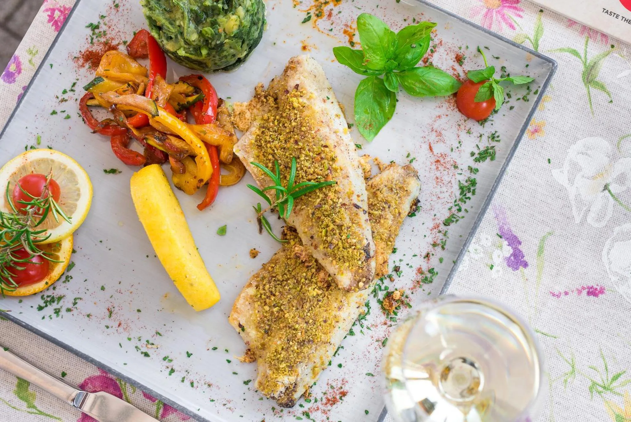 Assiette de poisson grillé accompagnée de légumes et d'une tranche de citron.
