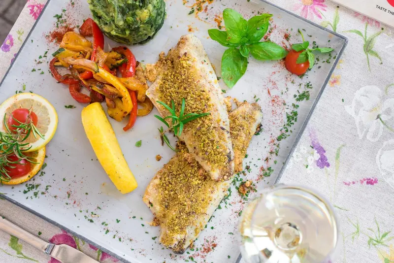 Assiette de poisson grillé accompagnée de légumes et d'une tranche de citron.