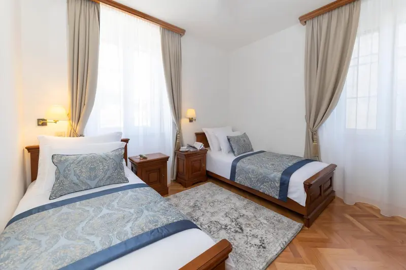 Une chambre lumineuse avec deux lits simples et un tapis.