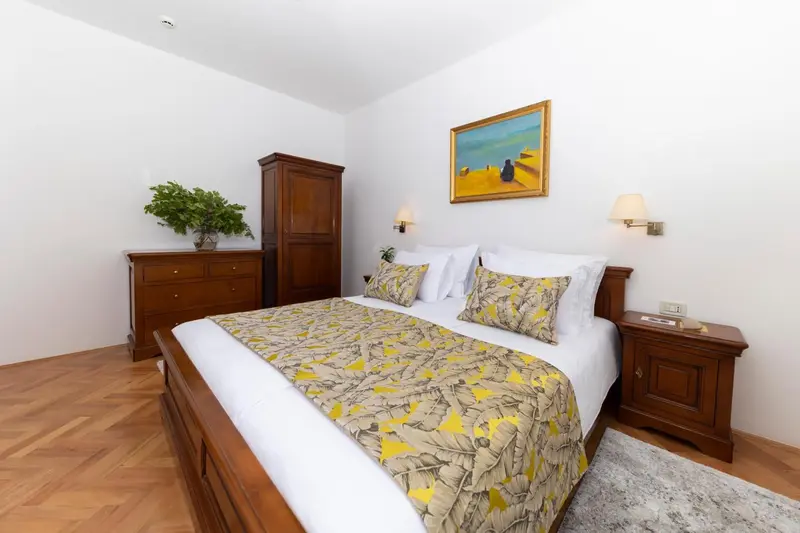 Une chambre lumineuse avec un grand lit et un meuble en bois.
