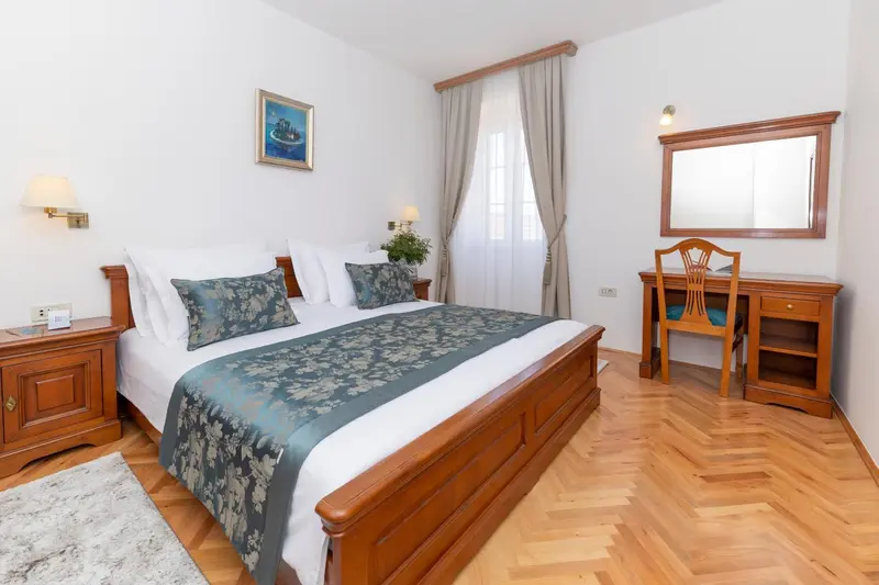 Une chambre lumineuse avec un grand lit et un bureau en bois.