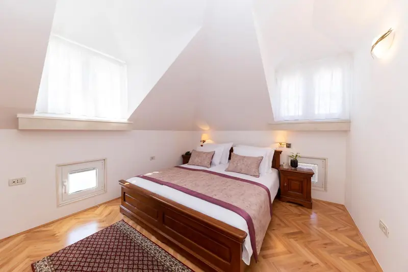 Une chambre lumineuse avec un grand lit et un parquet en bois.