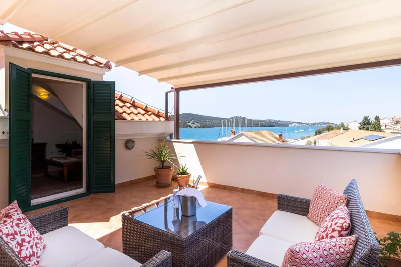 Terrasse aménagée avec salon de jardin et vue sur la mer.