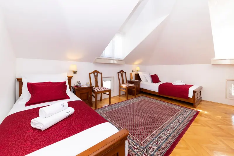Chambre lumineuse avec deux lits simples et une décoration sobre.