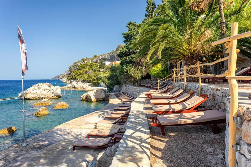 Transats alignés sur une terrasse ensoleillée au bord de la mer.