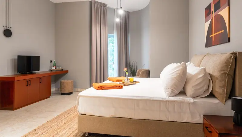 Une chambre lumineuse avec un grand lit et un meuble bas pour la télévision.