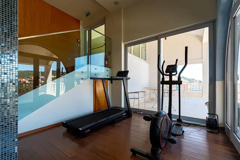 Une salle de sport lumineuse avec des équipements de fitness et une vue sur l'extérieur.