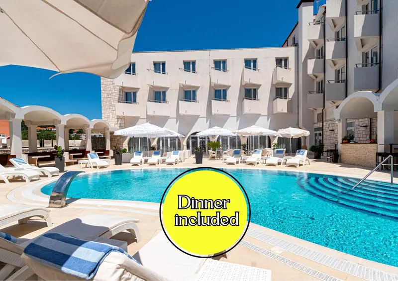 Une piscine turquoise bordée de transats blancs sous des parasols.