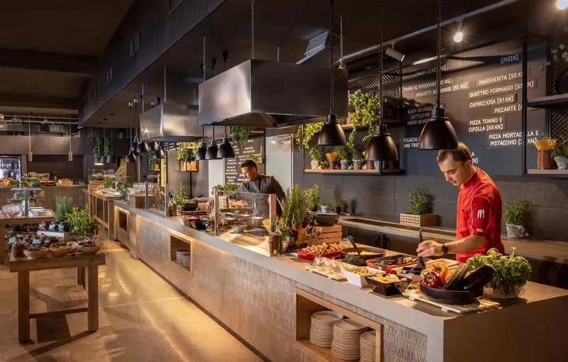 Un buffet propose une variété de plats et de salades dans un espace lumineux et moderne.