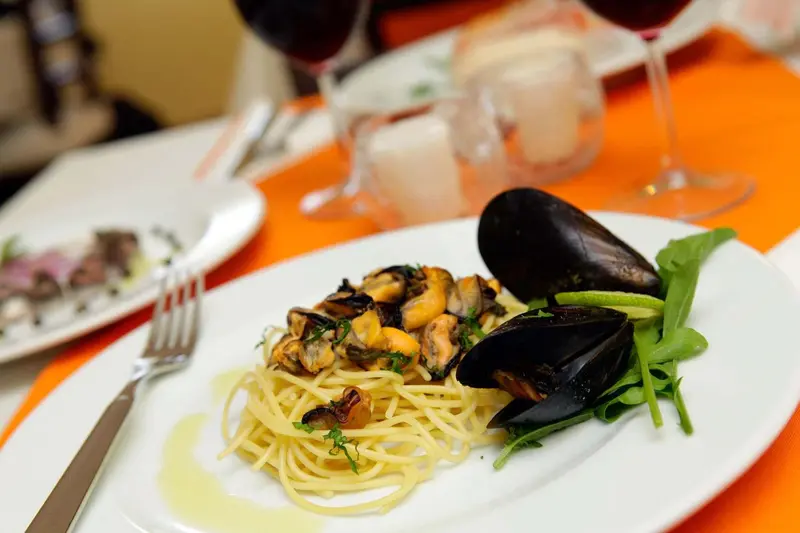 Assiettes de pâtes aux moules et fruits de mer sur une table dressée.