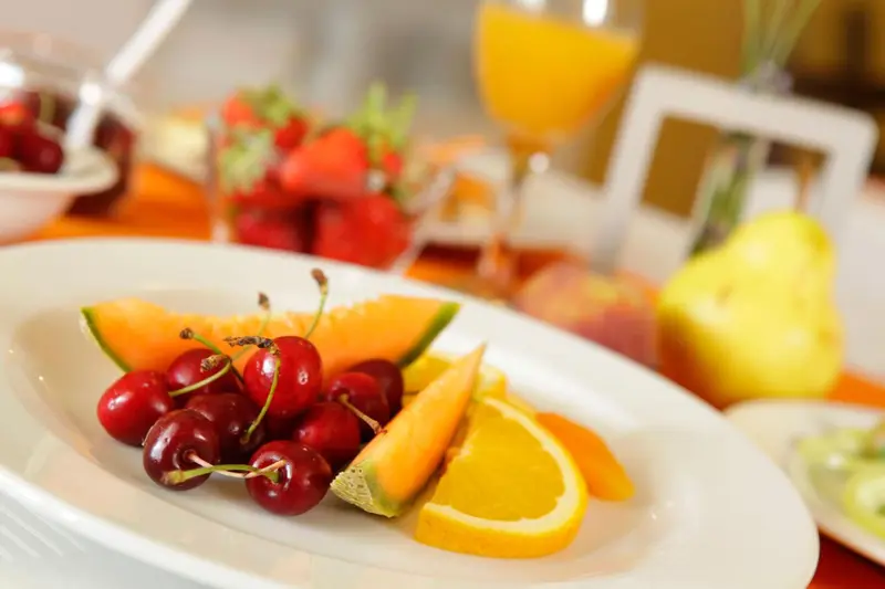 Une table est garnie de fruits frais et de jus d'orange.