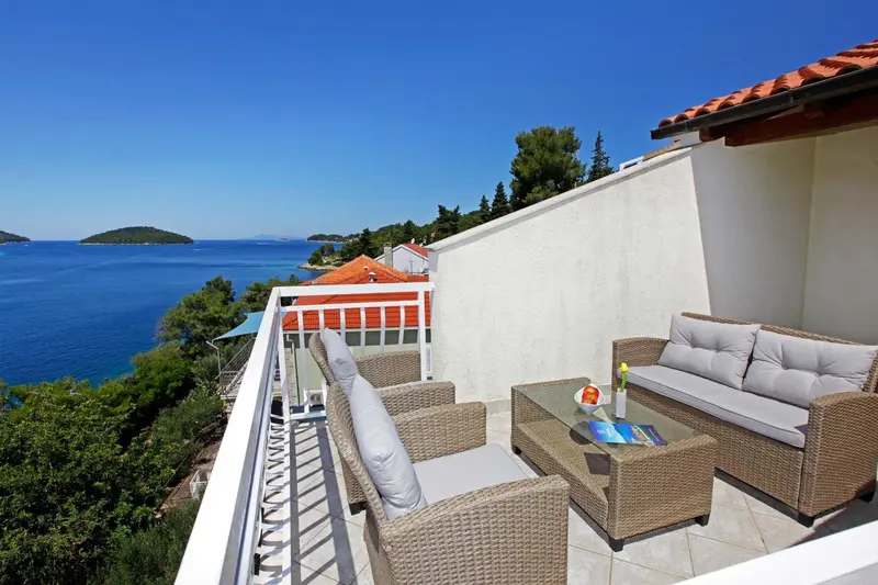Terrasse aménagée avec salon de jardin et vue sur la mer.