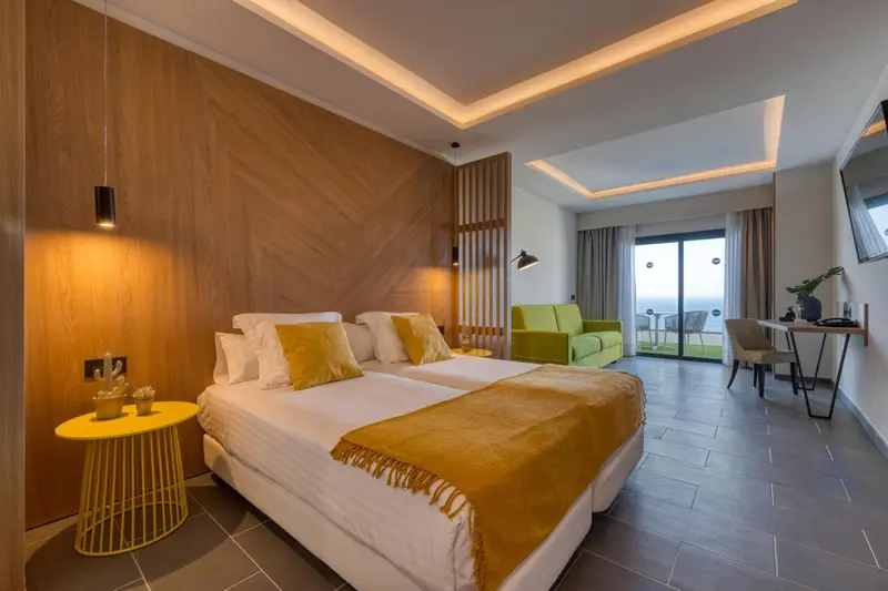 Une chambre lumineuse avec un lit double et un coin salon.