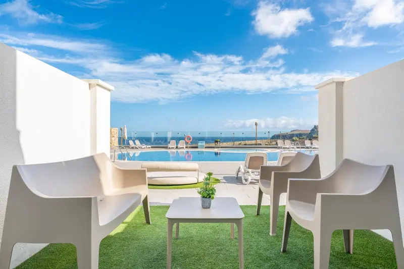 Terrasse avec mobilier d'extérieur donnant sur une piscine et la mer.