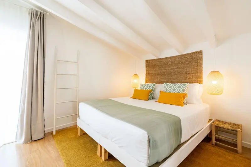 Une chambre lumineuse avec un lit recouvert d'une couette verte et de coussins jaunes.