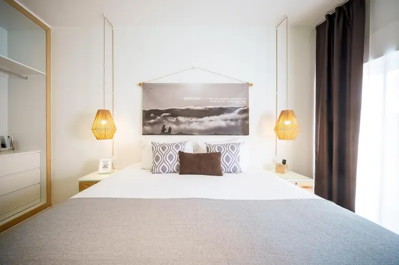 Une chambre lumineuse avec un grand lit et des luminaires suspendus.
