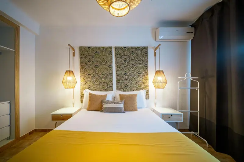 Une chambre lumineuse avec un grand lit recouvert d'une couverture jaune.