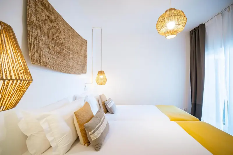 Une chambre lumineuse avec un grand lit recouvert d'oreillers et de coussins.