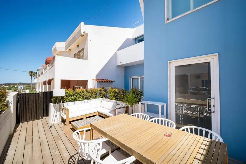 Terrasse aménagée avec mobilier blanc et table en bois.