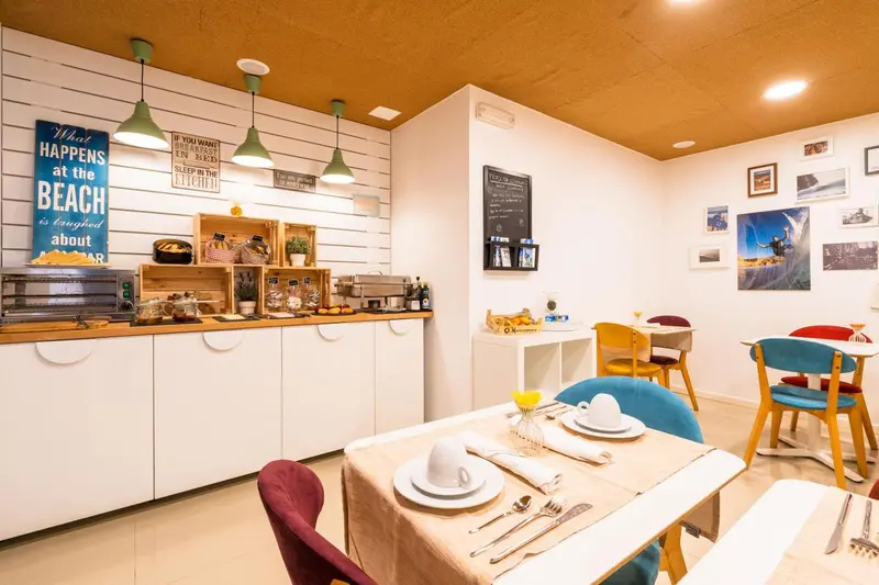 Une salle de restaurant lumineuse avec des tables dressées et une décoration murale.