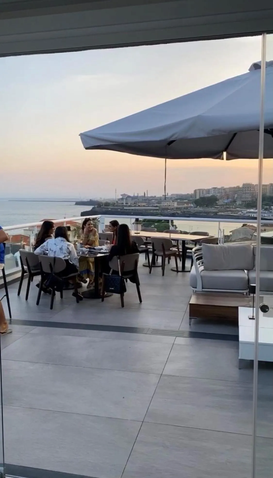 Des convives sont assis à une table sur une terrasse avec vue sur la mer.