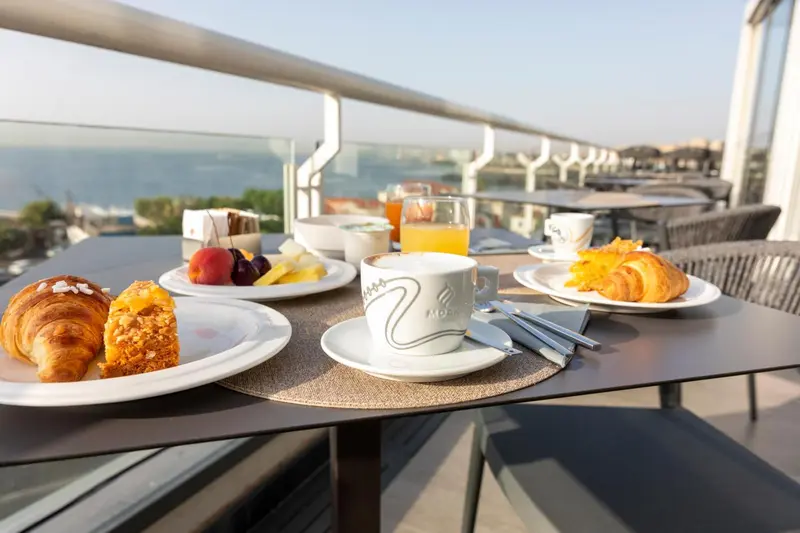 Une table est dressée avec un petit-déjeuner face à la mer.