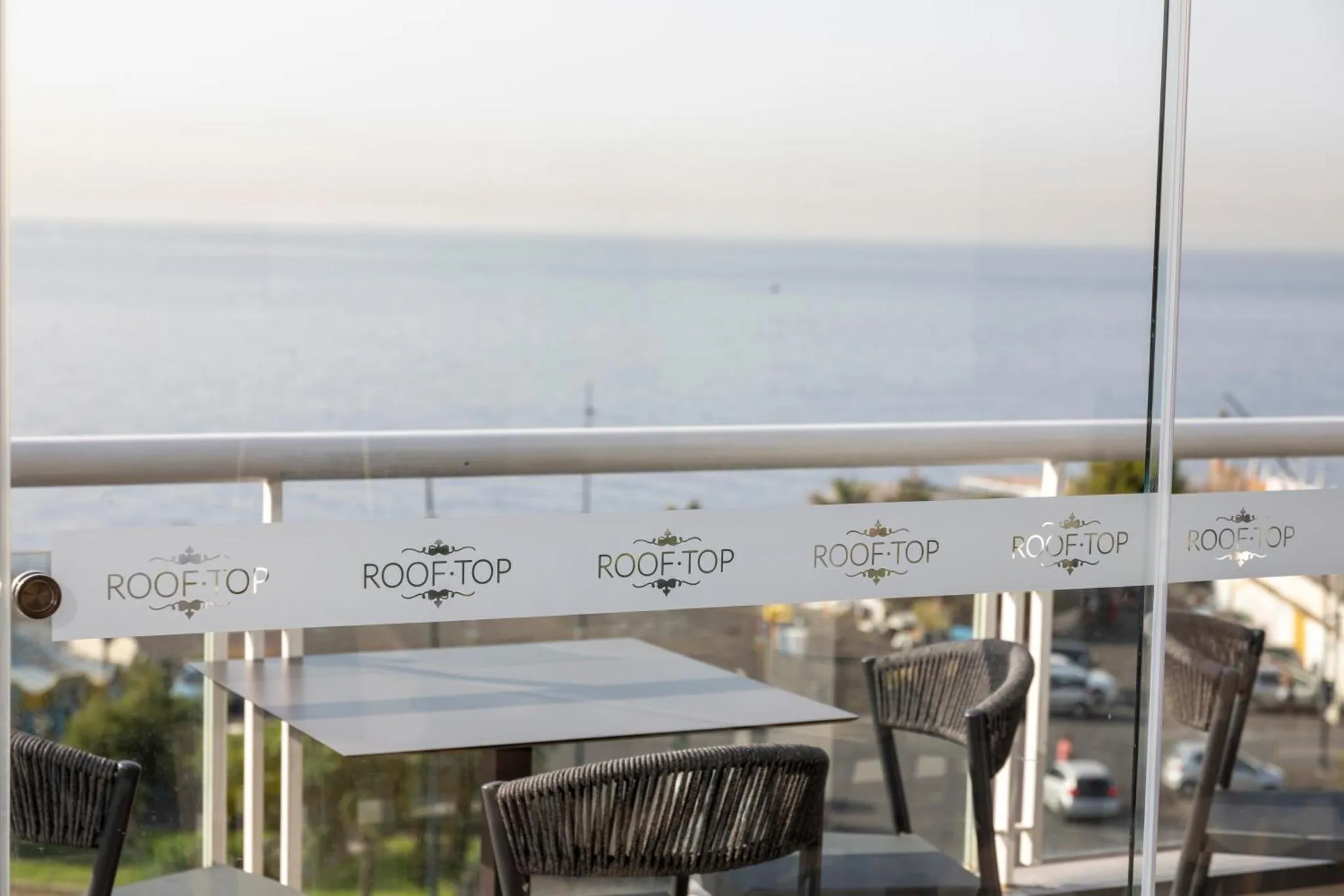 Terrasse avec tables et chaises donnant sur la mer.