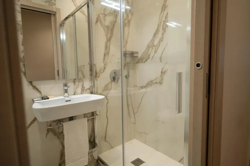 Une douche à l'italienne avec parois vitrées et lavabo.