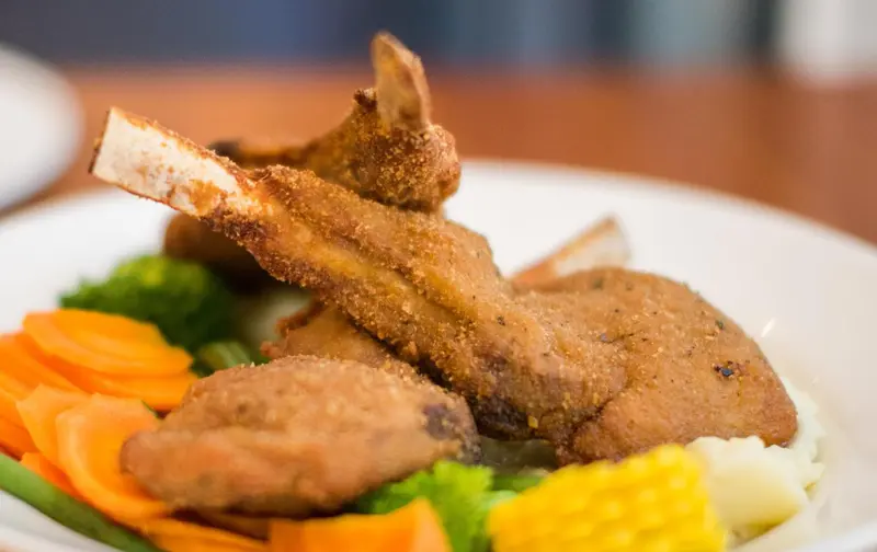 Assiette de viande panée accompagnée de légumes et de purée.