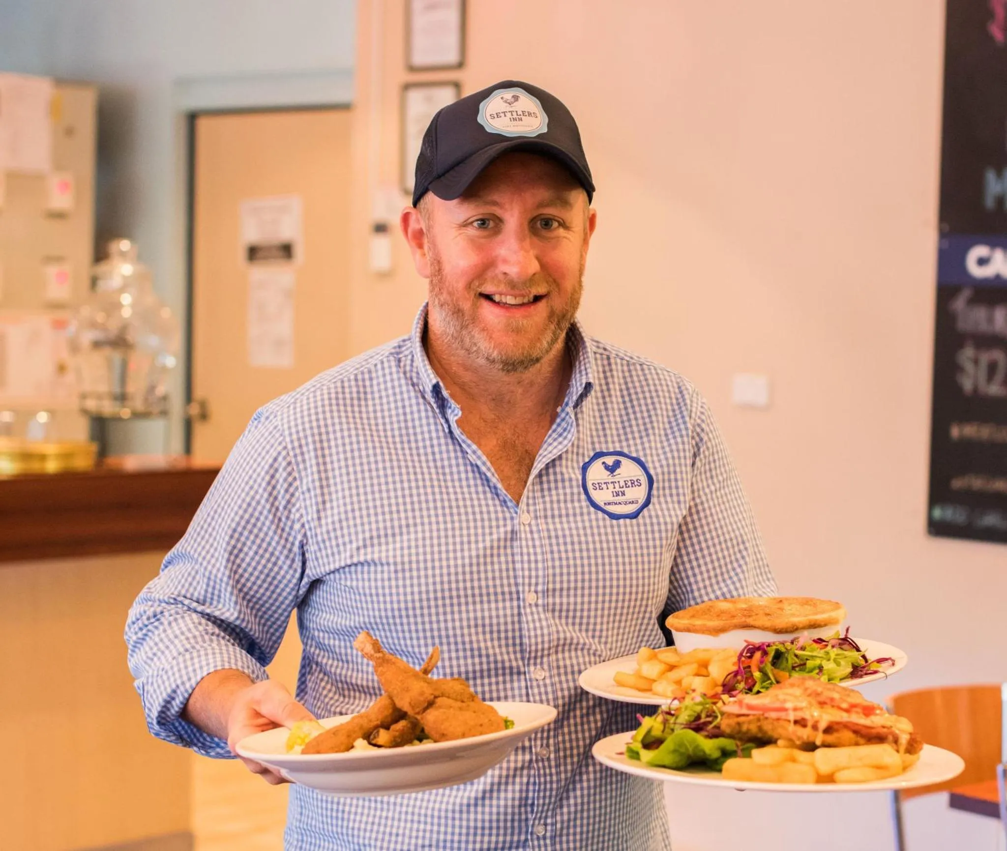 Un homme souriant présente des assiettes de nourriture.
