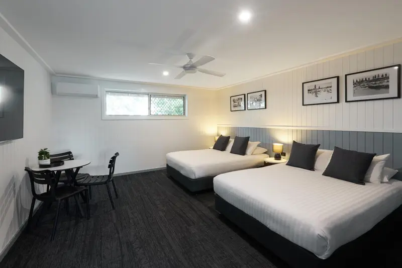 Une chambre lumineuse avec deux lits et un coin repas.