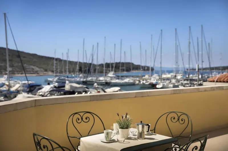 Une table est dressée sur une terrasse avec vue sur un port de plaisance.