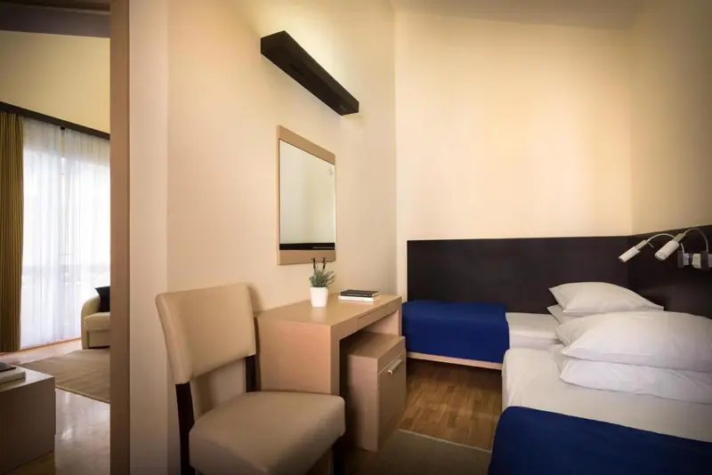 Une chambre avec un bureau et deux lits simples.