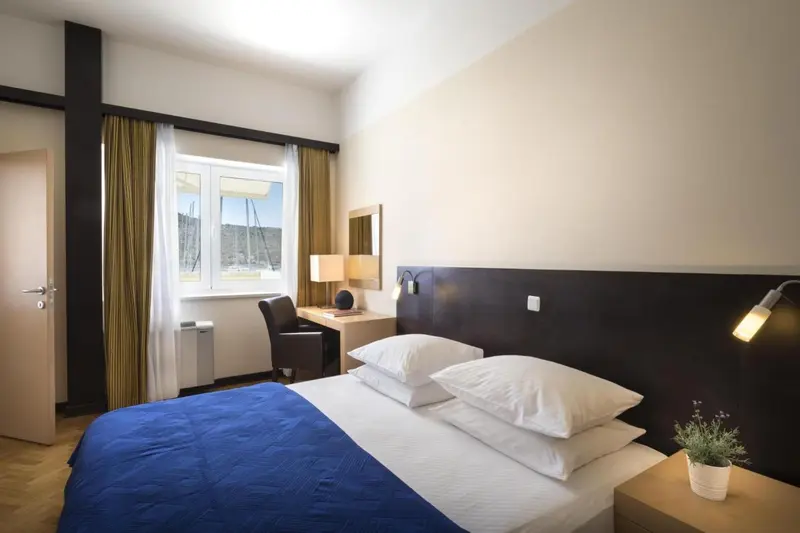 Une chambre lumineuse avec un lit et un bureau près d'une fenêtre.