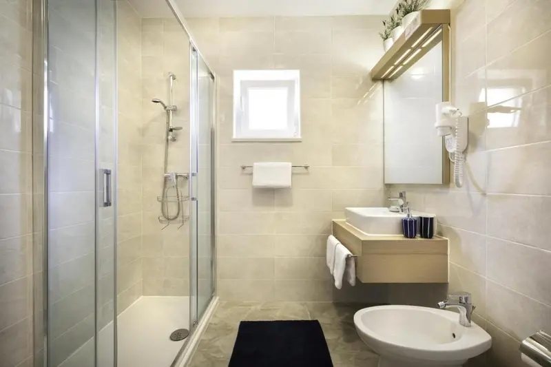 Une salle de bain claire avec douche à l'italienne et vasque.