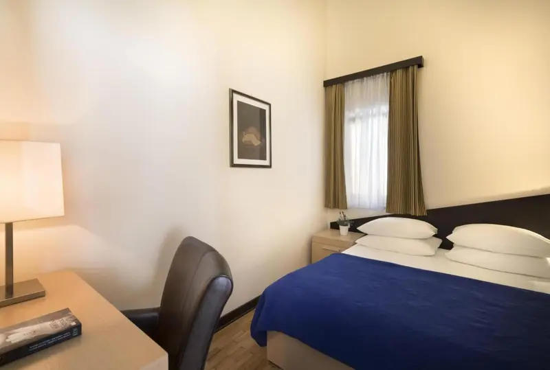 Une chambre lumineuse avec un lit fait et un bureau.