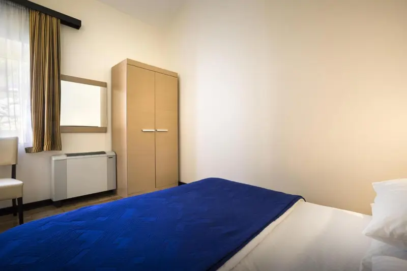 Une chambre avec un lit recouvert d'une couverture bleue et un grand placard.