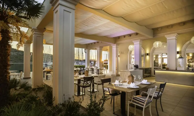 Une salle à manger lumineuse avec des tables dressées et un bar en fond.