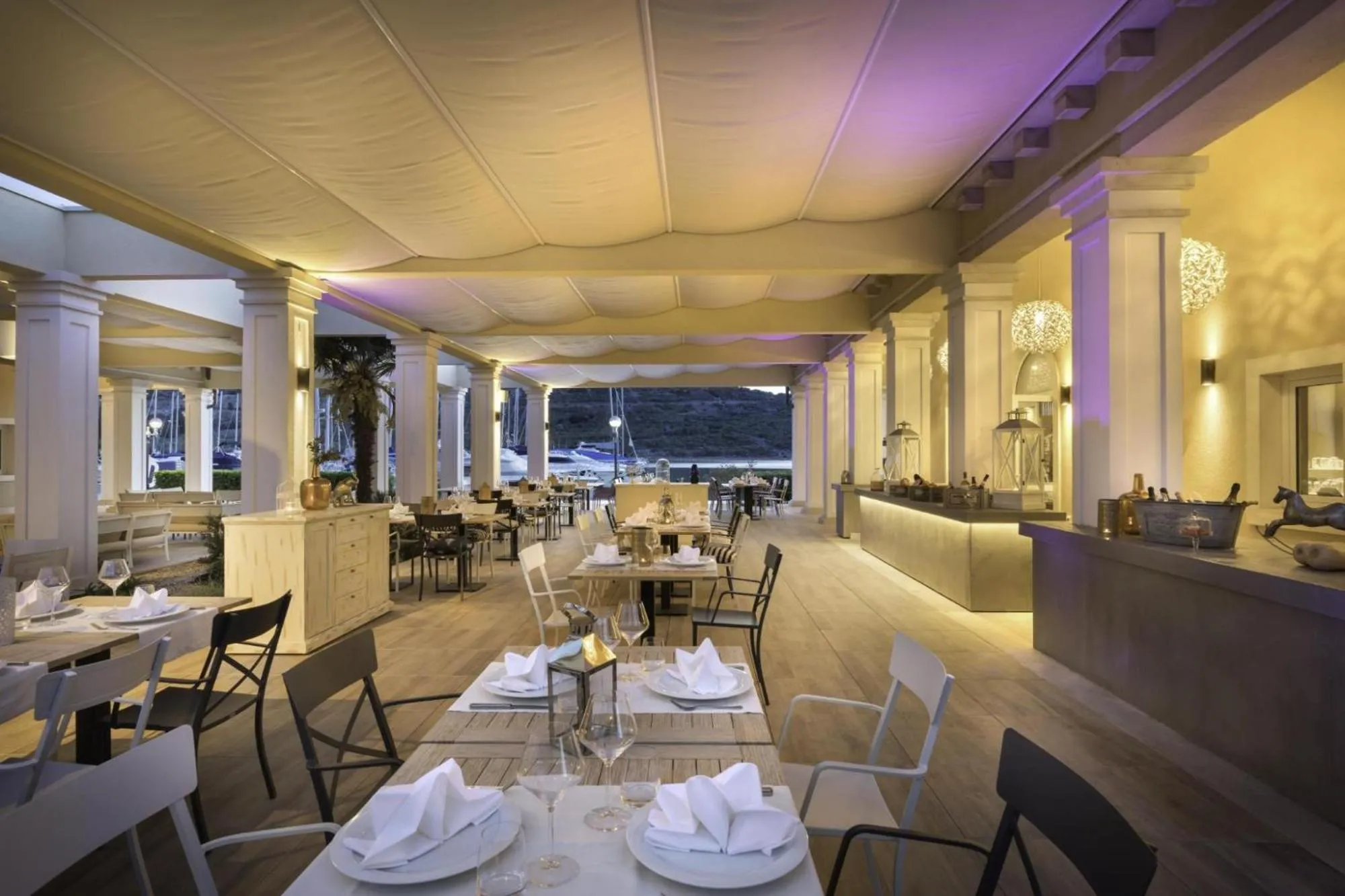 Une salle de restaurant lumineuse avec des tables dressées et un comptoir de bar.
