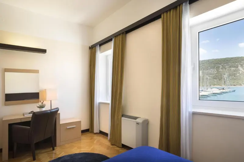 Une chambre lumineuse avec un bureau et une vue sur un port de plaisance.