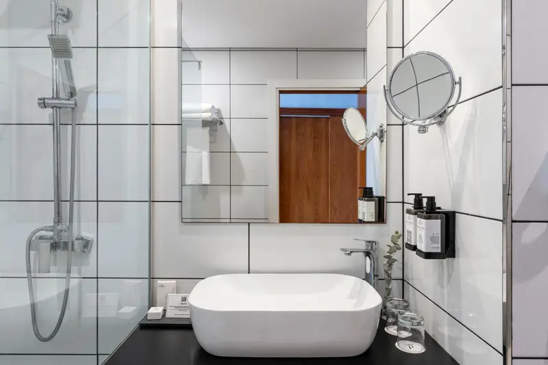Une salle de bain moderne avec douche à l'italienne et vasque blanche.
