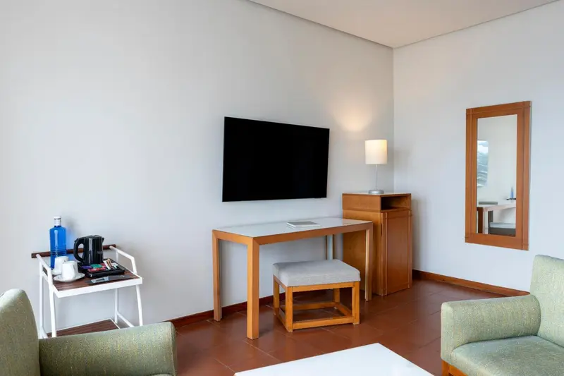 Une chambre lumineuse avec un bureau et un téléviseur mural.