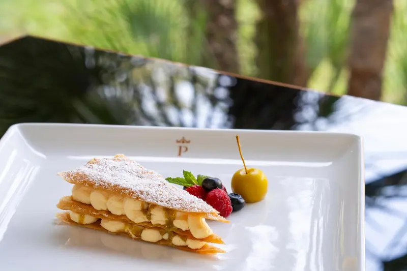 Une part de dessert à la crème est présentée sur une assiette blanche avec des fruits rouges.