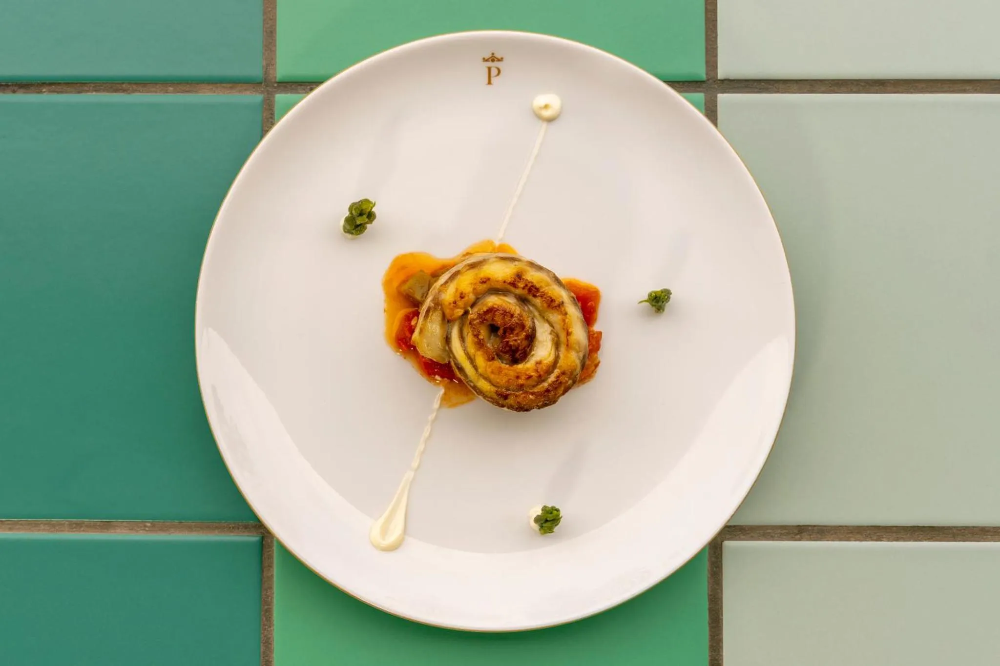 Assiette blanche ornée d'un plat à base de légumes enroulés et de sauces.