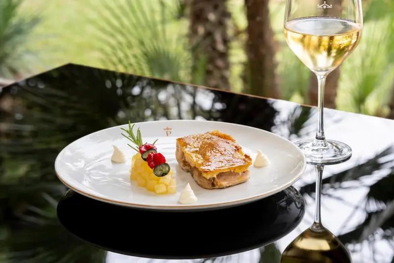 Assiette raffinée avec une préparation gastronomique et un verre de vin.