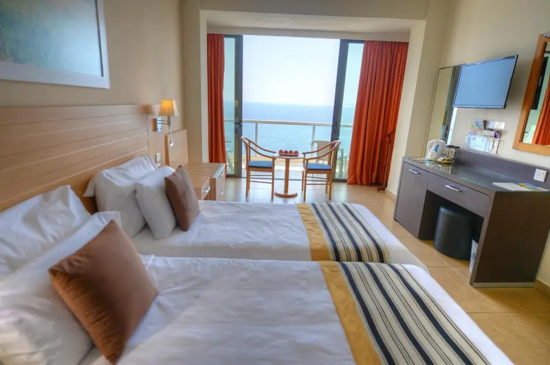 Chambre lumineuse avec lits jumeaux et vue sur la mer.
