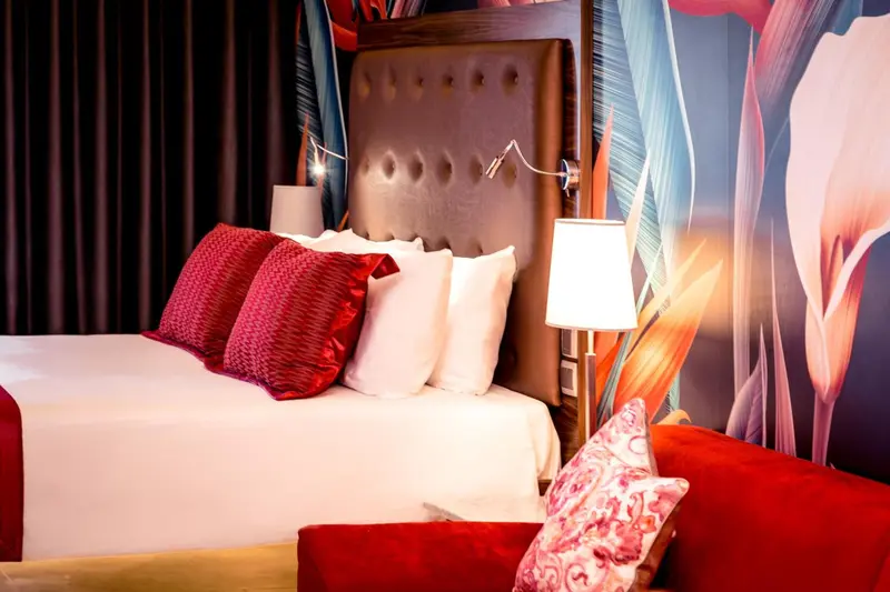Un lit avec des oreillers rouges et blancs dans une chambre décorée de motifs floraux.