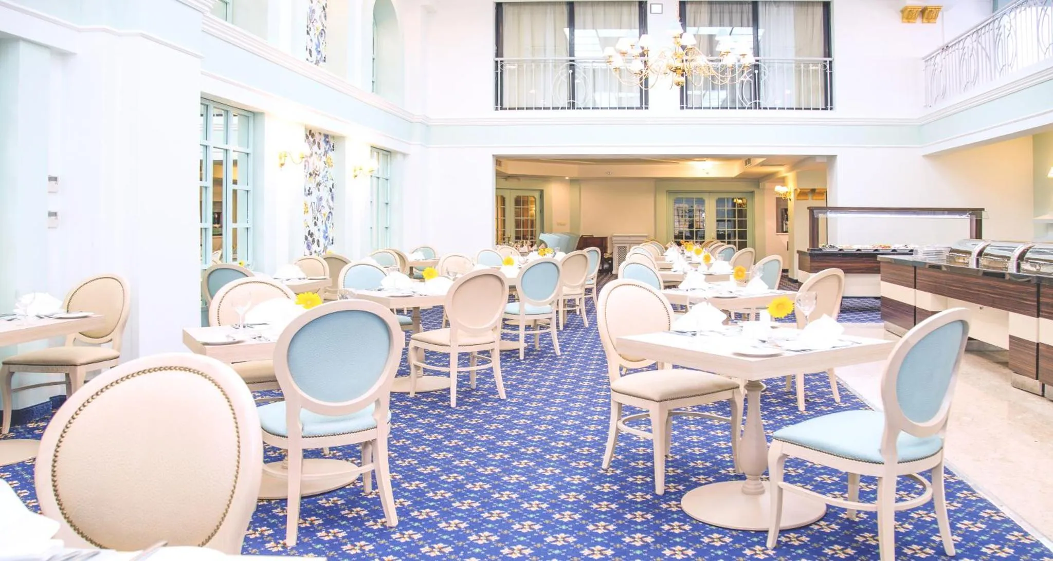 Une salle lumineuse est aménagée avec des tables et des chaises pour les repas.